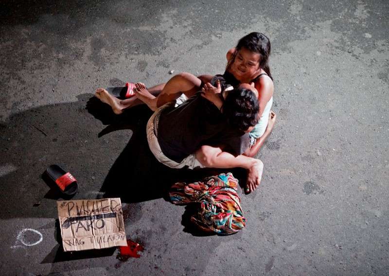 写真が語る16年 フィリピン麻薬戦争 夫を抱きかかえる女性