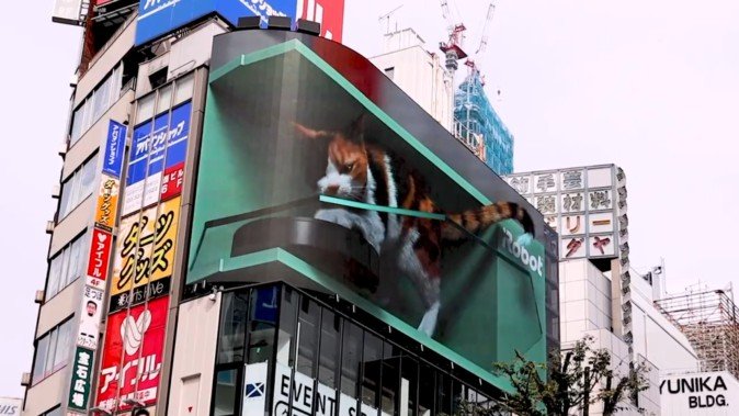 新宿駅前の巨大猫映像にルンバが登場 換毛期の猫の毛をお掃除