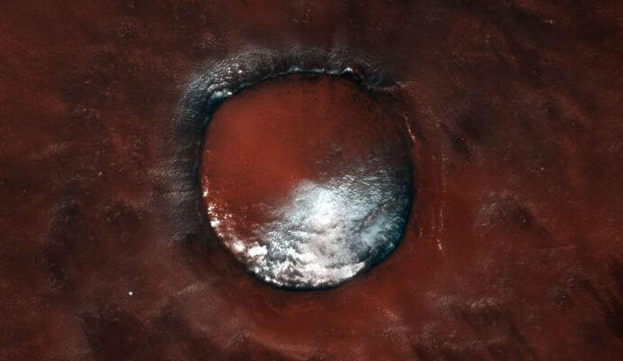 真っ赤な大地で白い氷を抱くクレーター。欧露の火星探査機「TGO」が撮影