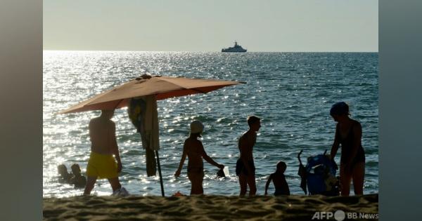 戦闘機と軍艦を眺めてロシア人観光客、クリミアのビーチで夏休み