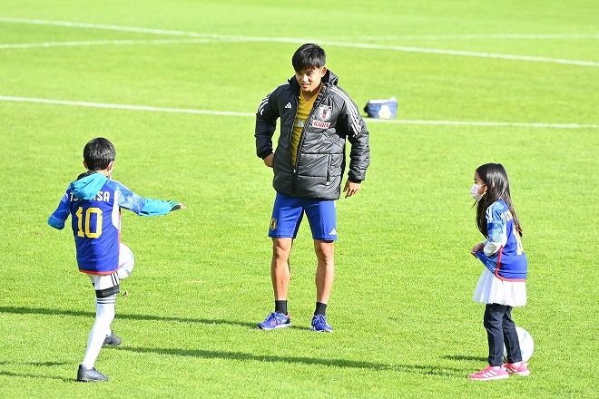 日本代表の微笑ましいワンシーン。久保建英が優しいアドバイスで子どもたちにサッカー指導