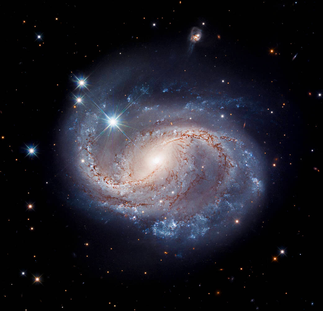 漆黒の宇宙空間と青い渦。棒渦巻銀河「NGC 6956」