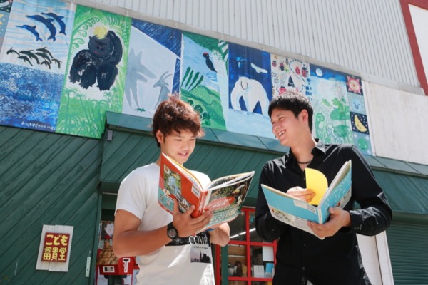 絵本を手にし、楽しそうな表情を浮かべる大谷翔平投手（右）と谷口雄也選手